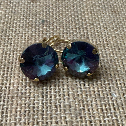 Pair of earrings with dark gemstones on a textured beige fabric background